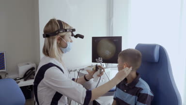 Doktor hasta kulak KBB teleskopla incelemek ve monitör ekranında bakın. Küçük çocuk kontrol otolaryngologist modern kliniğinde kulağına.