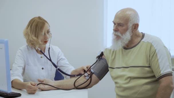 医師は メカニックの眼圧計と年配の男性のパルスをチェックします 老人の心に問題があるし 彼は心臓を訪問 — ストック動画