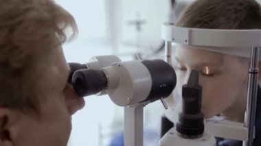 Doktor kontrol küçük çocuklar görme modern ekipmanla donatılmış. Güzel bir çocuk üzerinde düşünülmeli bakmak ve gözlerini hareket etme. Küçük çocuğun tanılama görme.