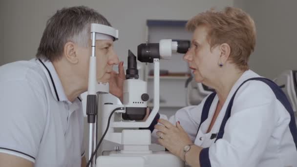 医生检查老人的视力与现代设备 老头看着眼科 别动他的眼睛 养老金的诊断视力 — 图库视频影像