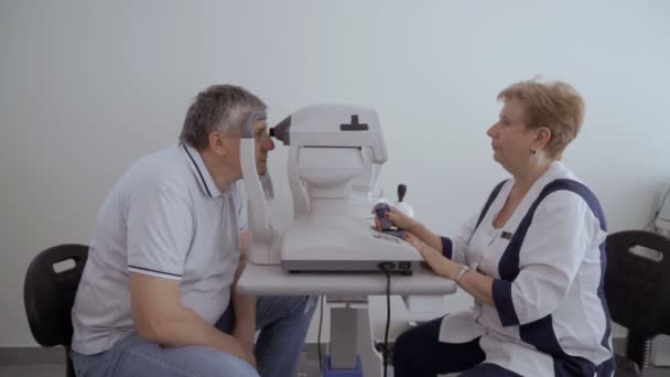 Arzt Überprüft Die Sehkraft Des Älteren Mannes Mit Moderner Ausrüstung — Stockvideo