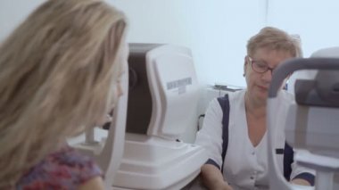 Doktor görme genç kadının modern ekipmanla donatılmış kontrol. Uzun saçlı kadın üzerinde düşünülmeli bakın ve onu sonuçlara dinleyin. Kadın tanılama görme.