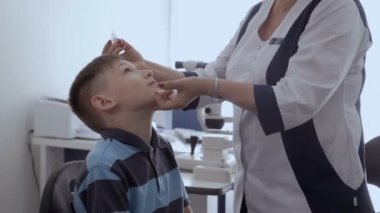 Doktor damla biraz sabırlı gözünde bırakır. Göz doktoru resepsiyonda küçük çocuk.