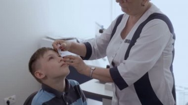 Doktor damla biraz sabırlı gözünde bırakır. Göz doktoru resepsiyonda küçük çocuk.