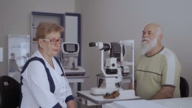 Doktor hasta ile görme kontrol prosedürü sonra konuşuyor. Adam neye optik modern cihazların yakınında oturan doktor.