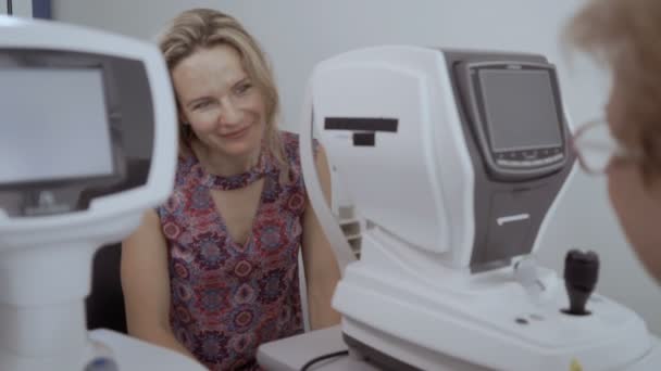医師は 近代的な設備を持つ若い女性の視力をチェックしました 長い髪の女性は Oculist の目し 耳で彼女の結論 女性の診断視力 — ストック動画