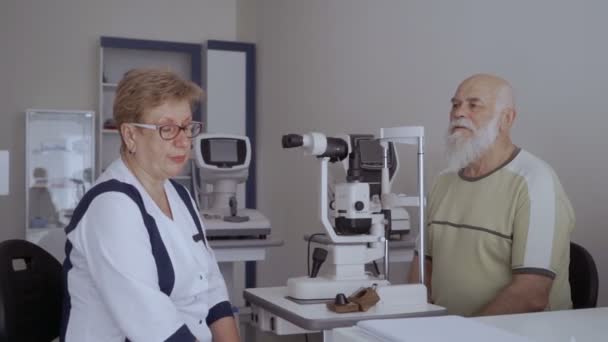 医師は 視力のチェックの手順の後 患者と話しています 現代の光学機器のそばに座って医者の男見て — ストック動画