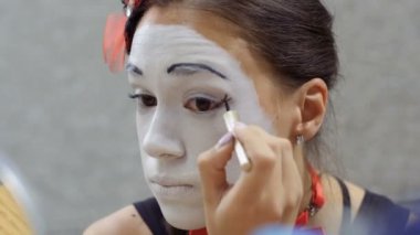 Genç kız boya siyah çizgiler kapaklarını. Sokak MIME kentsel sokaklarda Show'da hazırlanın. Güzel genç amatör insanlar küçük sahneler gösteriyor para kazanmak.