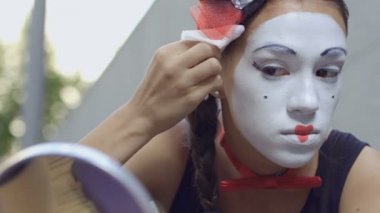 Genç kız doğru ve yüzünde peçete beyaz boya ile silin. Sokak MIME kentsel sokaklarda Show'da hazırlanın. Güzel genç amatör insanlar küçük sahneler gösteriyor para kazanmak.