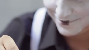 Genç adam, yüzünde beyaz boya koymak. Sokak MIME kentsel sokaklarda Show'da hazırlanın. Yakışıklı genç amatör insanlar küçük sahneler gösteriyor para kazanmak.