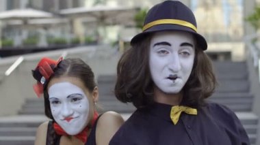 İki komik pandomim olay oynamak. Kız ve adam gesticulates onların yüz ifadeleri. Genç Amatör insanlar kentsel sokakları küçük komik sahneler gösteriyor para kazanmak.