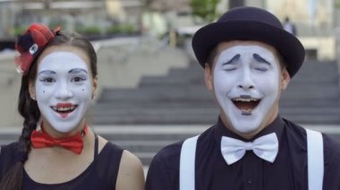 İki komik pandomim olay oynamak. Kız ve adam gesticulates onların yüz ifadeleri. Genç Amatör insanlar kentsel sokakları küçük komik sahneler gösteriyor para kazanmak.