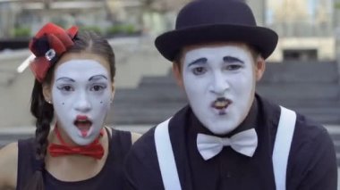 İki komik pandomim olay oynamak. Kız ve adam gesticulates onların yüz ifadeleri. Genç Amatör insanlar kentsel sokakları küçük komik sahneler gösteriyor para kazanmak.