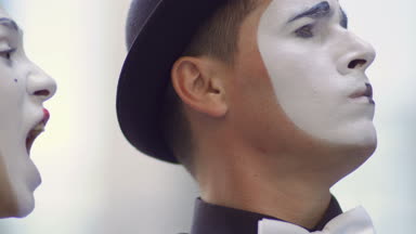 İki komik pandomim olay oynamak. Kız ve adam gesticulates onların yüz ifadeleri. Genç Amatör insanlar kentsel sokakları küçük komik sahneler gösteriyor para kazanmak.