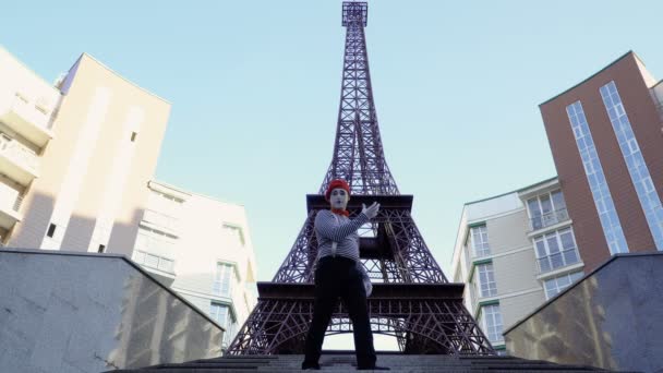 Muž na sobě mime svlékl košili a červený baret pózuje pro kamery a Eiffelova věž. Pouliční herec vydělávat peníze hrát legrační rolí a jeho výraz ve tváři.