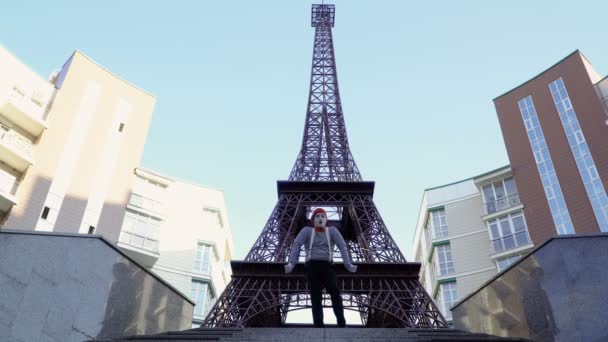 Muž na sobě mime svlékl košili a červený baret pózuje pro kameru v blízkosti Eiffelovy věže. Pouliční herec vydělat peníze zábavné role hrát a hrát si s jeho výrazy obličeje.