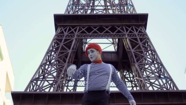 男子哑剧身穿脱衣服和红色贝雷帽在埃菲尔铁塔附近拍照 街头演员赚取金钱扮演有趣的角色和玩他的面部表情 — 图库视频影像