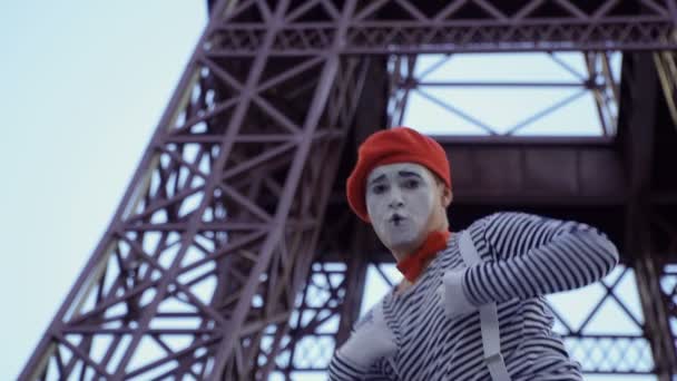 男子哑剧身穿脱衣服和红色贝雷帽在埃菲尔铁塔附近拍照 街头演员赚取金钱扮演有趣的角色和玩他的面部表情 — 图库视频影像