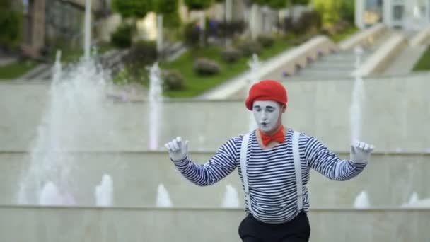 滑稽的 Mime 在红色贝雷帽准备在喷泉背景的性能 穿脱衣服的男人是街头演员 为人们演奏滑稽场面 — 图库视频影像