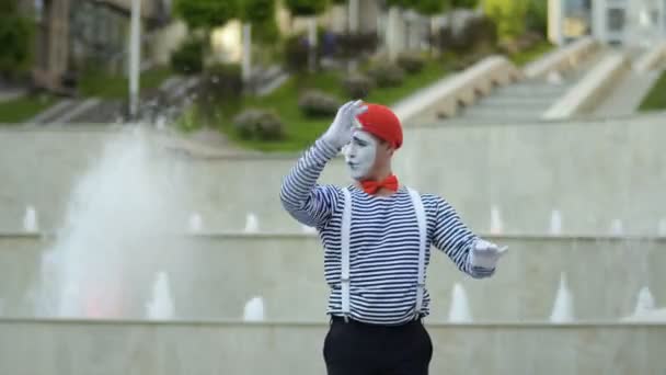 滑稽的 Mime 在红色贝雷帽有在喷泉 Bakcground 的表现和移动他的手作为指挥 穿脱衣服的男人是街头演员 为人们演奏滑稽场面 — 图库视频影像