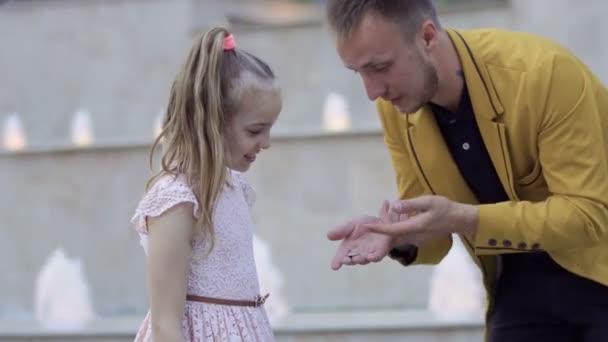 Goochelaar Toon truc met munt aan een klein meisje — Stockvideo