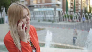 Kırmızı ceketli telefon ayakta Çeşme arka plan, konuşurken çekici kız