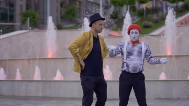 Magicien et mime s'amusent debout à l'arrière-plan des fontaines illuminées — Video