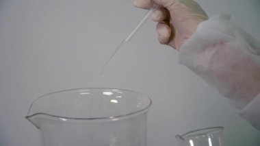 Bilim adamı damla sıvı içine bir ölçü cupwith pipet. Laboratuvar deneyi sıvı ile.