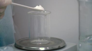 Kimyager kuru toz teraziler üzerinde bir ölçü fincan içine koymak. Toz ağırlığını ölçmek bilim adamı. Yakın çekim.