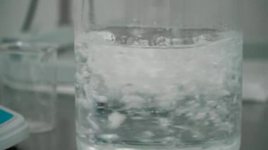 Toz ve liqiuid cam fincan içinde cam çubukla karıştırma kimyager. Toz ve sıvı deney için karıştırma bir bilim adamı. Yakın çekim.