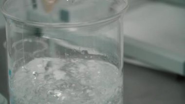 Toz ve liqiuid cam fincan içinde cam çubukla karıştırma kimyager. Toz ve sıvı deney için karıştırma bir bilim adamı. Yakın çekim.