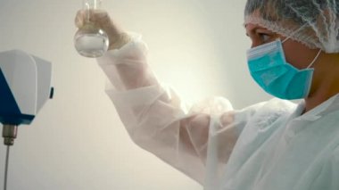 Bir şişe sıvı karıştırma kimyager. Laboratuvar çalışan sıvı deneme için hazırlanıyor. İlaç makinesi arka plan çalışma.