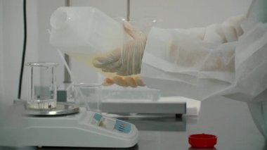 Viskoz sıvı elektronik ölçekte bir şişesi içine dökme kimyager. Bilim adamı Deney Laboratuvar donatımı hazırlanıyor. Yakın çekim.