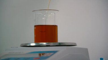 Bir pipet ile elektronik ölçekte bir şişesi içine sıvı dökme kimyager. Deney Laboratuvarı ve mesuring için donatım hazırlanıyor bilim adamı o. Yakın çekim.