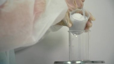 Kimyager kuru toz teraziler üzerinde bir ölçü fincan içine koymak. Toz ağırlığını ölçmek bilim adamı. Yakın çekim.