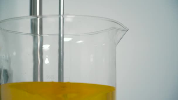 将粘稠橙液混合在玻璃杯中搅拌 在实验室里实验液体 — 图库视频影像