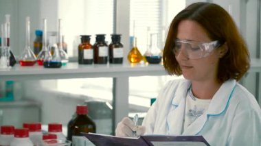 Eczacı Not defterini içinde olun. Raflar ile arka plan bulanık, renkli reaktifler.