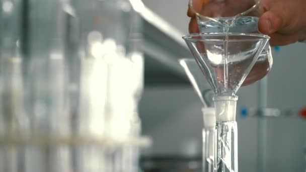 化学家通过漏斗将酒精倒入瓶中 科学家在实验室里用液体工作 照相机在运动中 — 图库视频影像