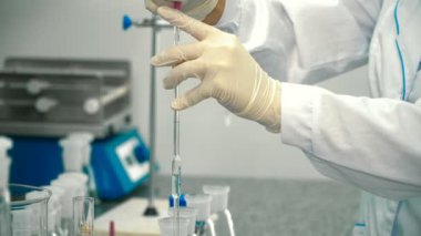 Bilim adamı şeffaf sıvı cam tüp içine dökün. Kimyager laboratuvar deneyi için sıvı ölçü birimi miktarı.