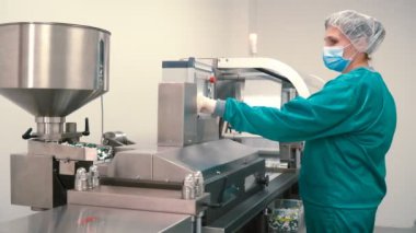 Alt kapsüller yapmak için ilaç makine ayarlayın. Koruyucu kıyafet ve maske giymiş laboratuvar çalışan modern tıbbi ekipman ile çalışma.