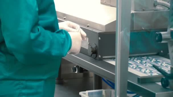 労働者は パッケージにカプセルを並べ替えのプロセスを制御します カプセルでコンベヤです 医薬品工場で近代的な設備 錠剤のゼラチン カプセルを作るための機械 — ストック動画