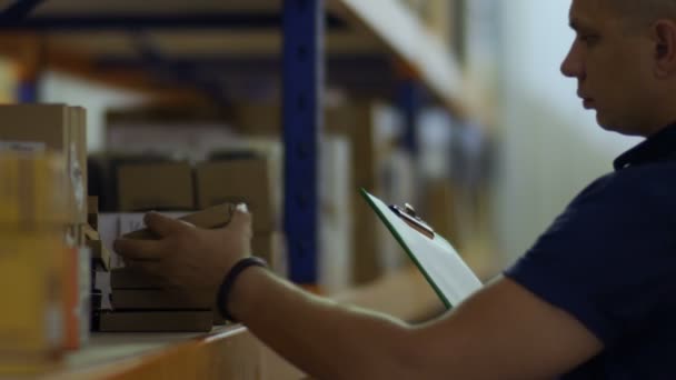 Supervisor check the packages on shelves in warehouse and writing report — Stock Video
