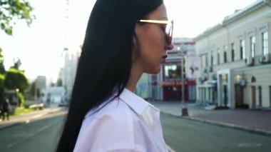 Şık güneş gözlüklü esmer güzel yürüyüş yavaş hareket kentsel cadde boyunca