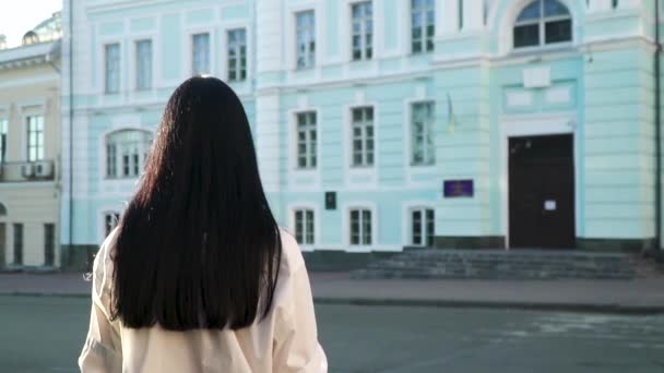 Brune élégante aux cheveux longs se déplaçant vers le bâtiment bleu au ralenti — Video