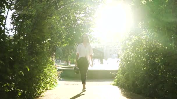 Elegante mujer joven en tacones altos caminando en el parque en el fondo de las fuentes — Vídeo de stock