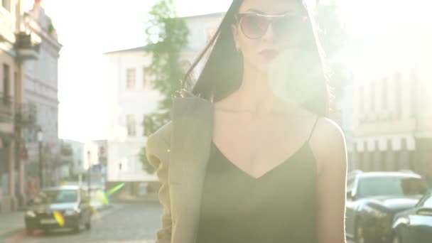 Modische Brünette mit Sonnenbrille läuft in Zeitlupe in Sonnenstrahlen auf der Straße — Stockvideo