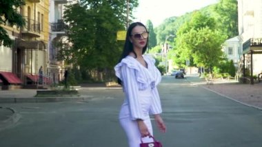 Zarif esmer beyaz etek, soyulmuş tunik ve güneş gözlüğü yürüyüş şehir