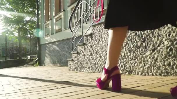 Mulher na moda sapatos roxos em saltos altos andando na rua em raios de sol — Vídeo de Stock