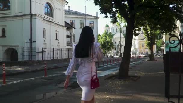 Trendy vrouw is in de ochtend op straat lopen en praten over de telefoon — Stockvideo