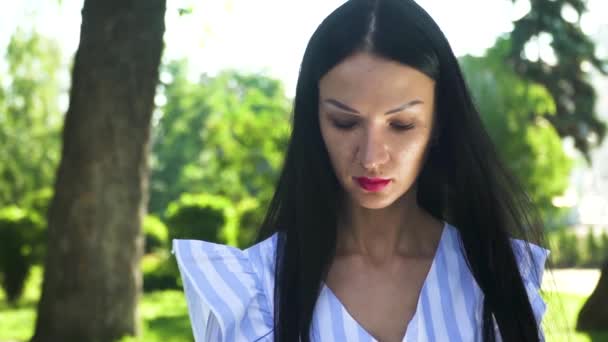 Portrait de belle brune regardant la caméra extérieure sur fond de parc d'été — Video